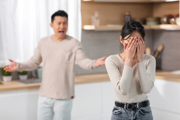 Emotional asian husband and wife having fight at kitchen - obrazy, fototapety, plakaty