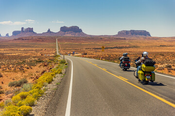 Classic panorama view of motorcyclist on historic U.S. Route 163 running through famous Monument Valley, Utah, USA