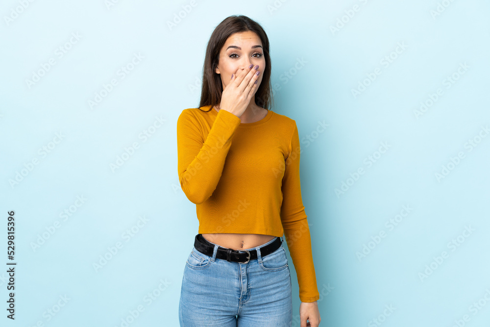 Canvas Prints Young caucasian woman isolated on blue background happy and smiling covering mouth with hand