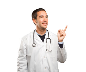 Surprised doctor pointing up against white background