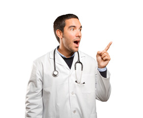 Surprised doctor pointing up against white background