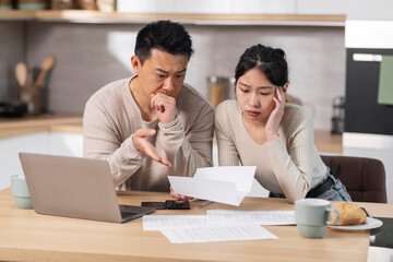 Fototapeta na wymiar Unhappy asian husband and wife reading letter, kitchen interior