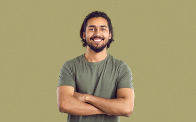 Portrait of happy young indian man with beautiful smile on khaki studio background. Bearded ethnic...