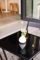 Bouquet of daisies in a white vase on the black glass table cafe outside