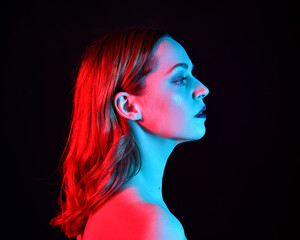 
Close up portrait of beautiful woman model, with pink and blue neon lighting in studio with dark background.