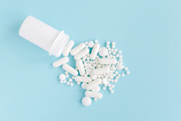 Scattered white pills on blue table. Mock up for special offers as advertising, web background or other ideas. Medical, pharmacy and healthcare concept. Copy space. Empty place for text or logo
