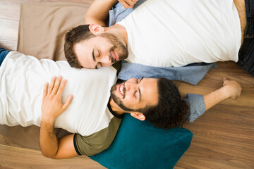 Relaxed gay couple lying on the floor at home and laughing