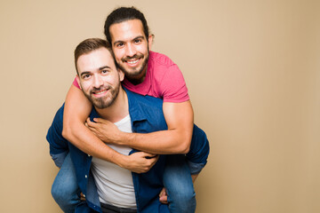 Portrait of a fun mixed-race cheerful gay couple piggybacking