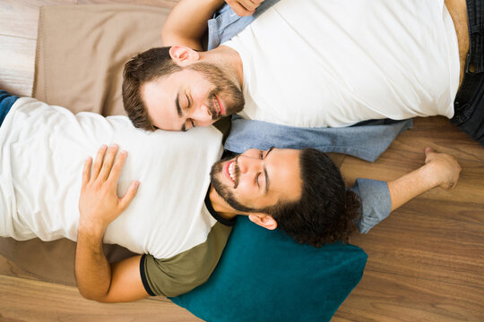 Relaxed gay couple lying on the floor at home and laughing