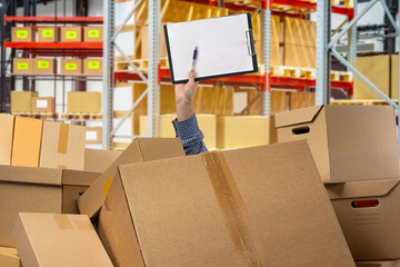 Stocktake at warehouse. Man hand with clipboard. Chaos boxes. Metaphor accounting courier boxes. Warehouse shelving blurred. Stocktake boxes. Warehouse lot with chaos. Working in logistics business - obrazy, fototapety, plakaty