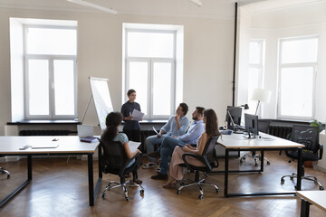 Presenter woman training diverse group of employees. Female coach giving workshop shop to staff on corporate meeting. Business team discussing project in office open space interior. Wide shot