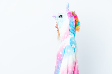 Blonde Uruguayan girl wearing a unicorn pajama isolated on white background laughing in lateral position
