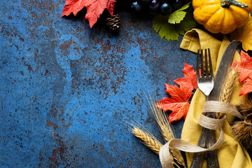 Hello Autumn concept with silverware and traditional fall decorations  - leaves, pumpkins, grapes, nuts and ponecones. Thanksgiving celebration  and harvesting