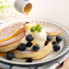 Delicious Japanese souffle pancake with blueberry, cranberry and honey on wooden table background.