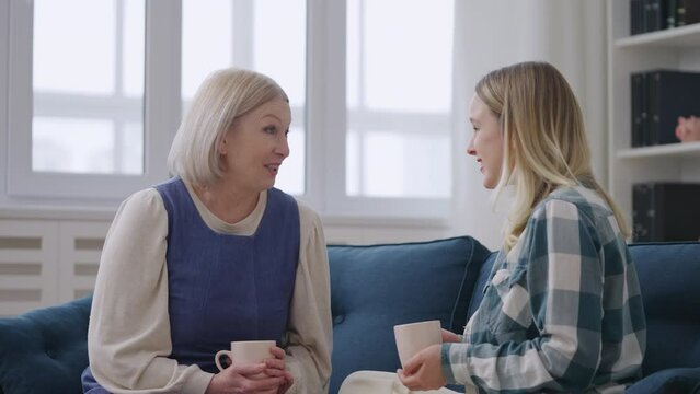 Cheerful woman talking with mother while drinking tea, trustful relationship