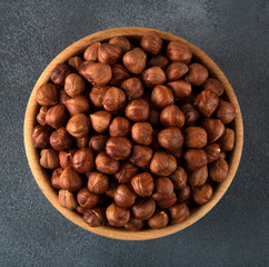 Top view of a bowl full of hazelnuts on dark background,square shape
