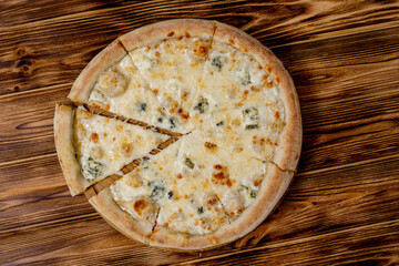 Pizza with four cheeses, mozzarella, blue cheese, Parmesan cheese. Italian cuisine. On a wooden background. View from above.