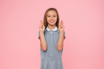 Happy caucasian young preteen teenage schoolgirl in blue dress crossing her fingers for good luck...