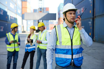 factory worker or engineer using walkie talkie and talking about work in containers warehouse storage
