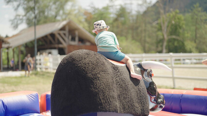 Kid on mechanical bull rodeo riding at western festival