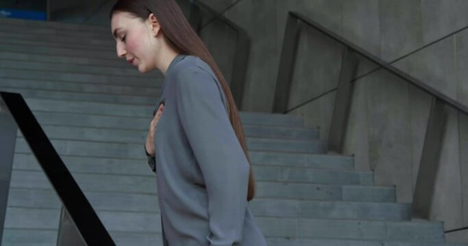 Woman having heart attack on stairs, outdoors
