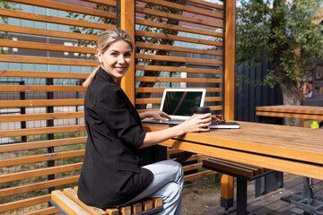 Business young woman with a laptop at a table in a cafe