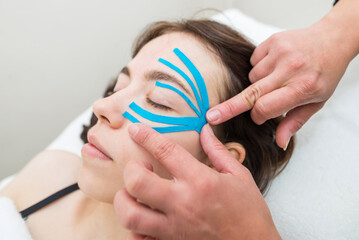 female cosmetician doing the taping of the face of the patient