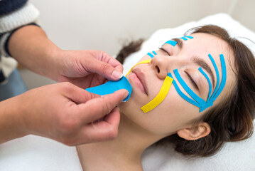 female cosmetician doing the taping of the face of the patient