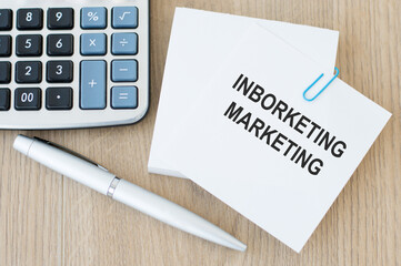 Inborketing marketing text card on a wooden table next to a pen and calculator
