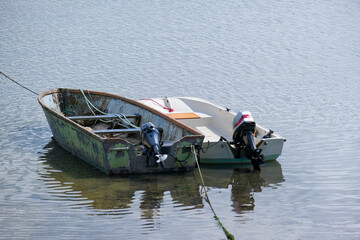 Alt und neu: Zwei Boote mit Außenbordmotor liegen nebeneinander vertäut auf dem Wasser