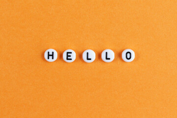 The inscription HELLO on an orange background. Greeting postcard. Minimalism. Copy space. view from above