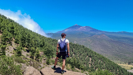 Fototapeta na wymiar Man with scenic view on volcano Pico del Teide surrounded by Canarian pine tree forest, Teno mountain, Tenerife, Canary Islands, Spain, Europe. Hiking trail from Santiago to Masca via Pico Verde