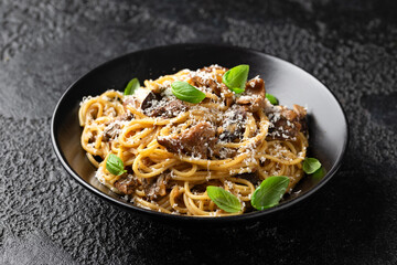 Porcini and woodland mushrooms pasta with pecorino cheese, basil in black bowl