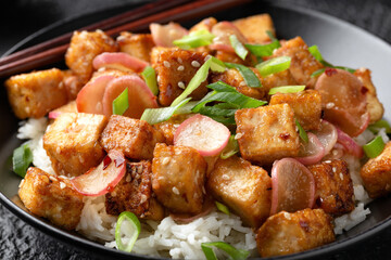 Fried tofu with radish, spring onion and garlic, ginger dressing in black bowl