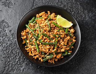 Pork Stir Fry with Green Beans, garlic, chili and ginger in black bowl. Asian food.