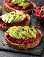 Avocado, beetroot hummus toast on dark sourdough bread topped with pumpkin, sunflower, hemp and flaxseed. Vegan, vegetarian super food