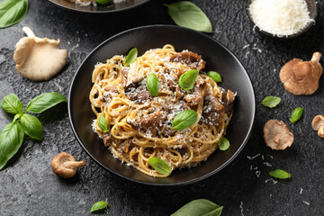 Porcini and woodland mushrooms pasta with pecorino cheese, basil in black bowl