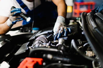 Close up mechanic working and checking engine in garage, Technician is wearing gloves and shine a...