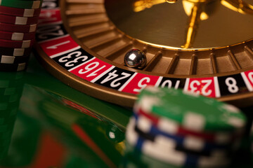 Obraz premium Casino. Roulette wheel and poker chips on the green shining background.
