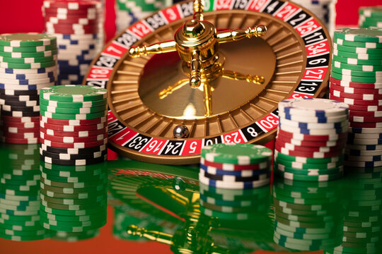 Casino. Roulette wheel and poker chips on the green shining background.