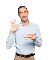 Young man using chopsticks to eat sushi