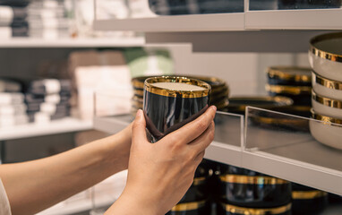 Woman holding a cup in the store, the concept of choosing dishes.