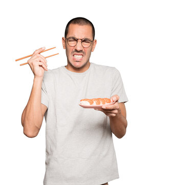 Young man using chopsticks to eat sushi