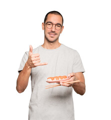 Young man using chopsticks to eat sushi