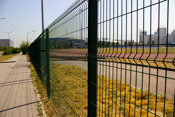 Obraz premium metal fence thin rods city stadium