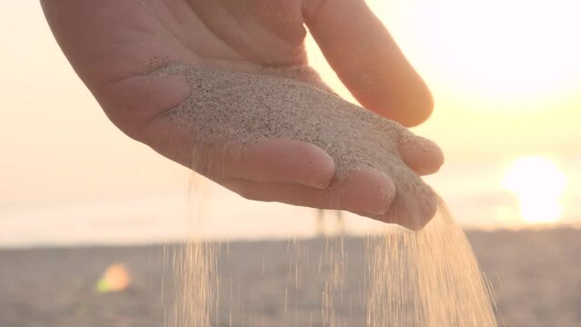 Poring sand from male hand in summer day on the beach. Summer vacation concept. Close up. 4k video