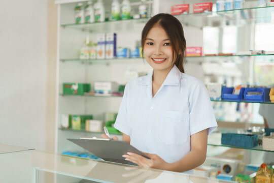 Medicine and health concept, Female pharmacist is checking stock medicine on clipboard in pharmacy