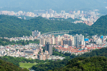 Overlooking the urban panoramic view of the Neihu and Nangang in Taipei, Taiwan, surrounded by green forests and mountains.