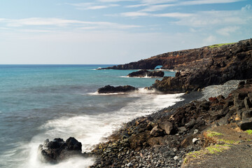 Rocky coastline reveals a view of a sea arch on Maui.