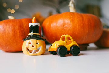 Happy Halloween. Kitchen decoration for Halloween. Pumpkin, funny lamp and taxi toy on the table.